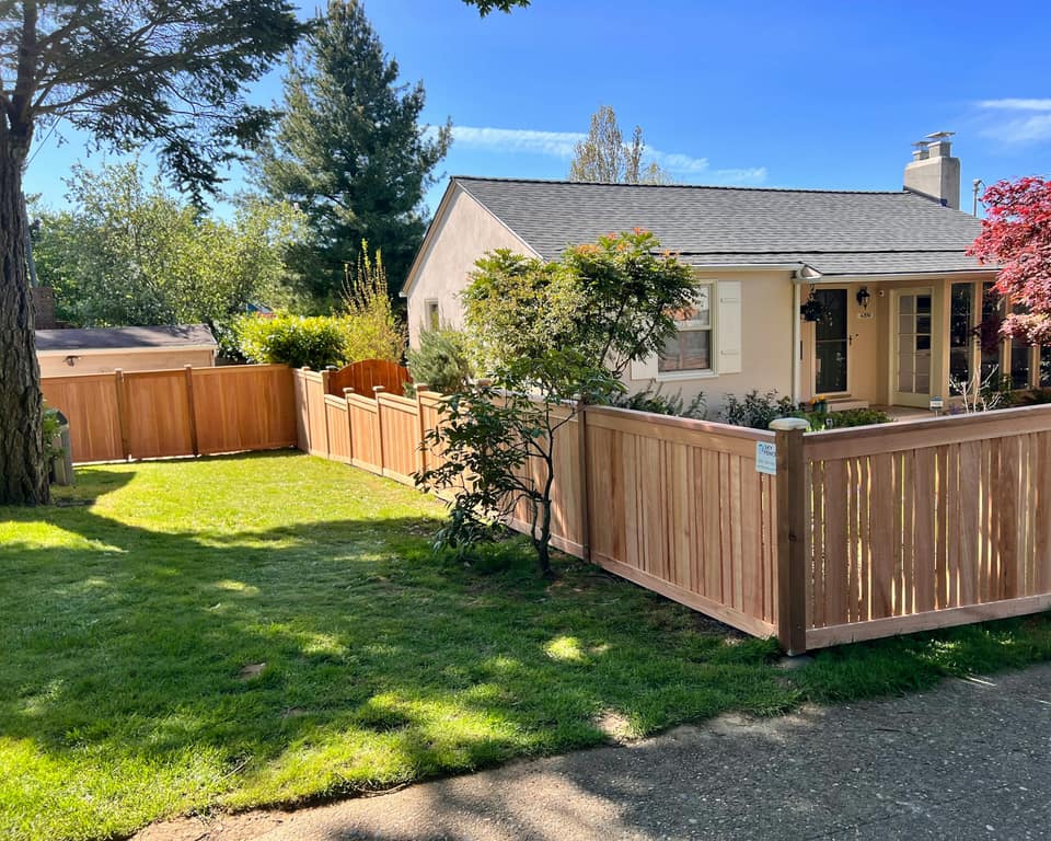 A new natural wood fence around the front yard of a single-story home.